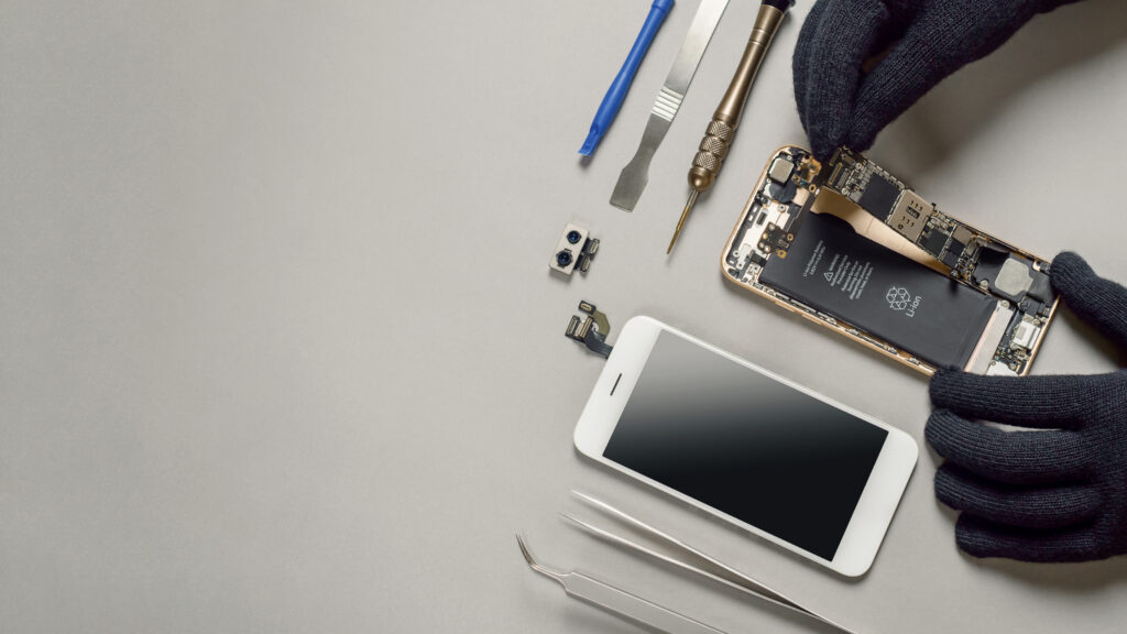 Technician repairing broken smartphone on desk