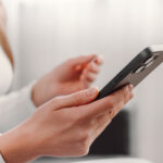 Close up of female hands holding phone in a mobile repair store